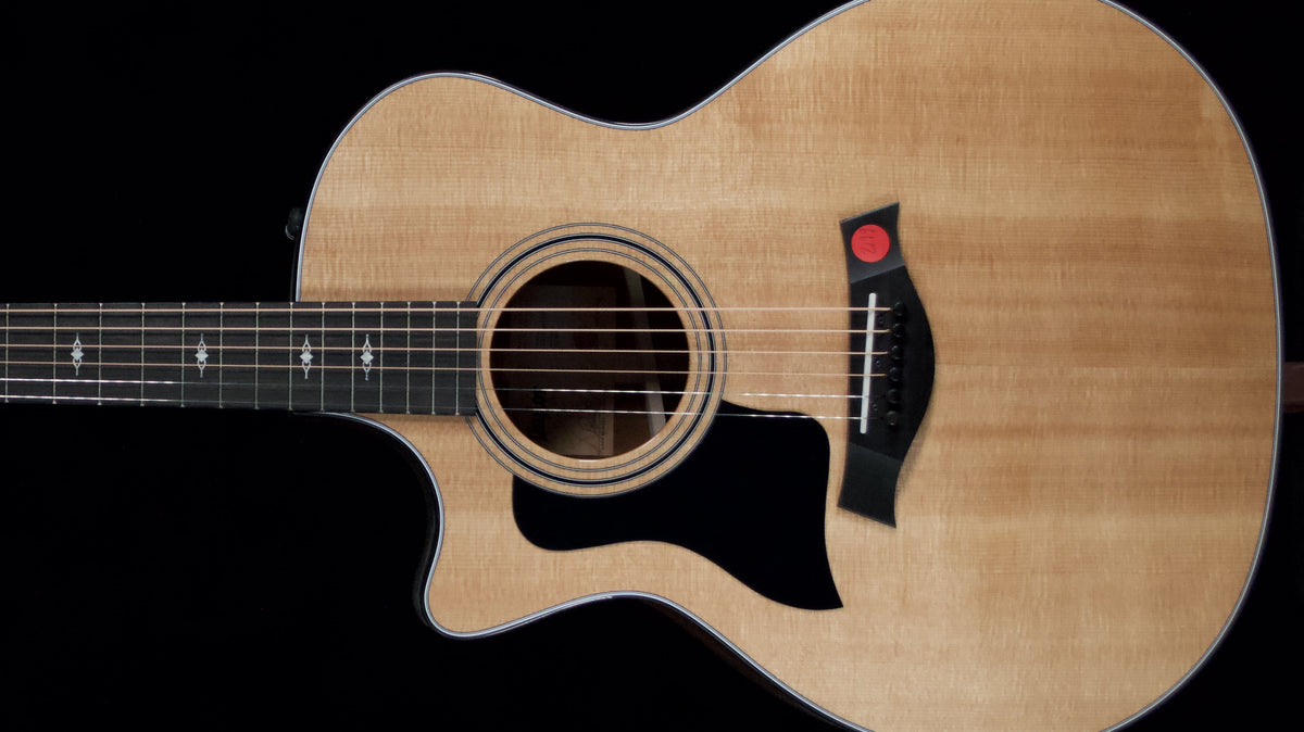 Natural-finish Taylor 314ce left-handed acoustic guitar with a cutaway and black pickguard against a black background