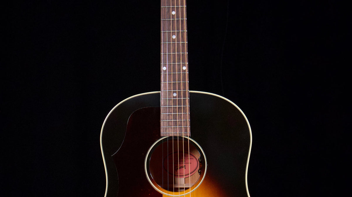 Vintage sunburst left-handed acoustic guitar against a dark background