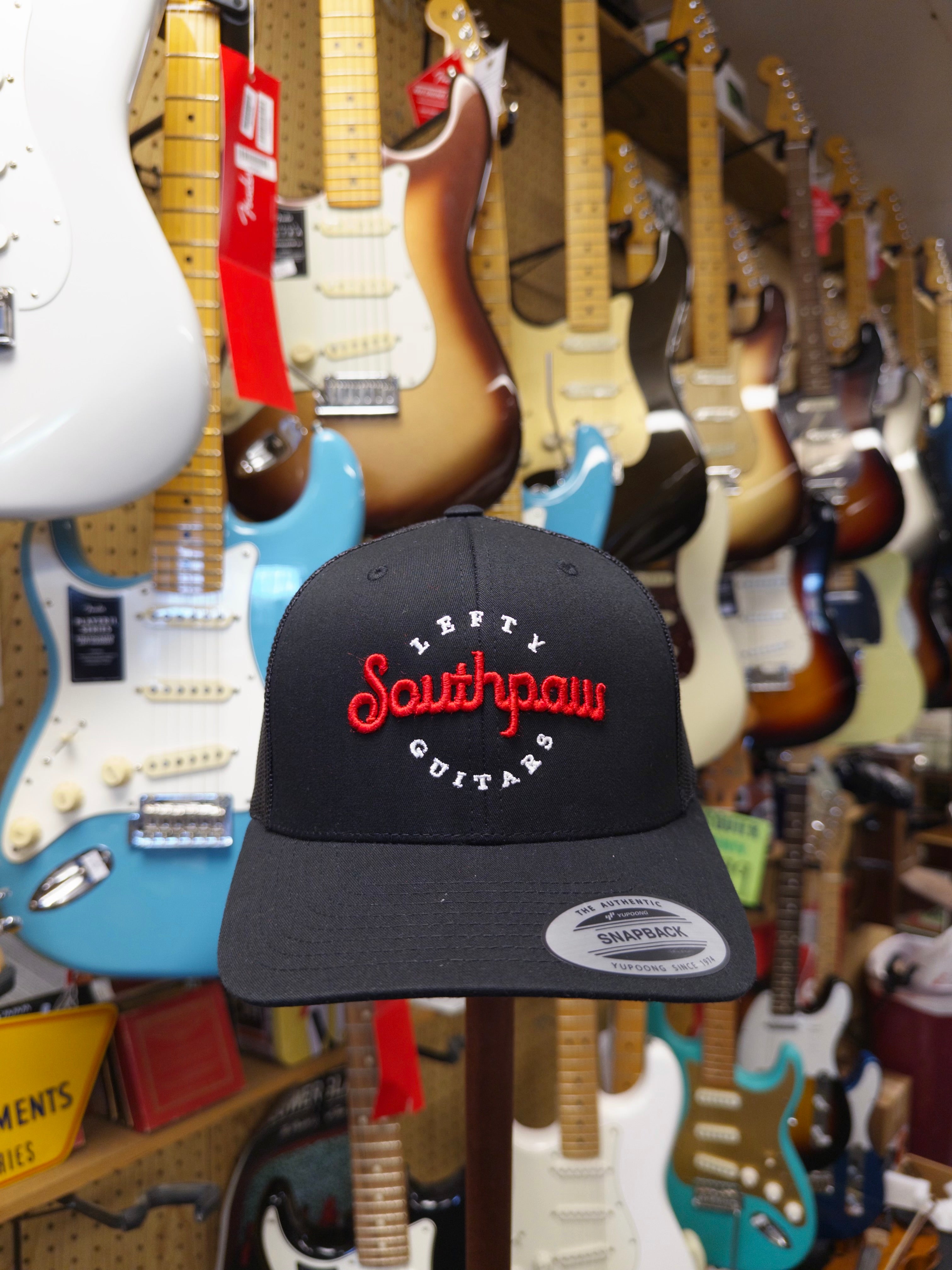 Black cap with 'Southpaws Guitar' logo in a guitar store setting