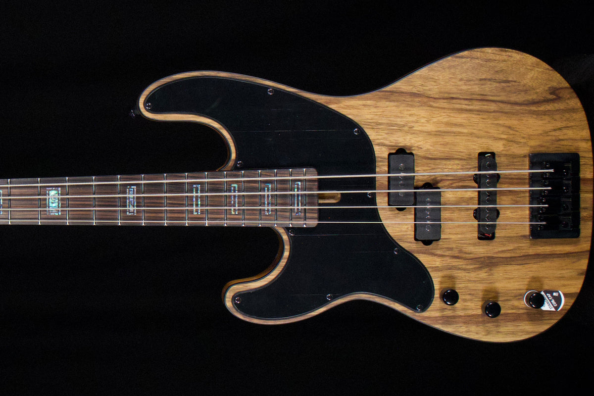 A four-string bass guitar with a natural wood grain body, black pickguard, and black hardware, shown against a solid black background.
