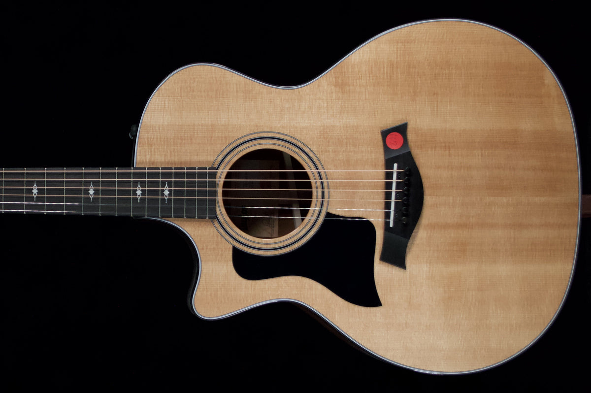Natural-finish Taylor 314ce left-handed acoustic guitar with a cutaway and black pickguard against a black background