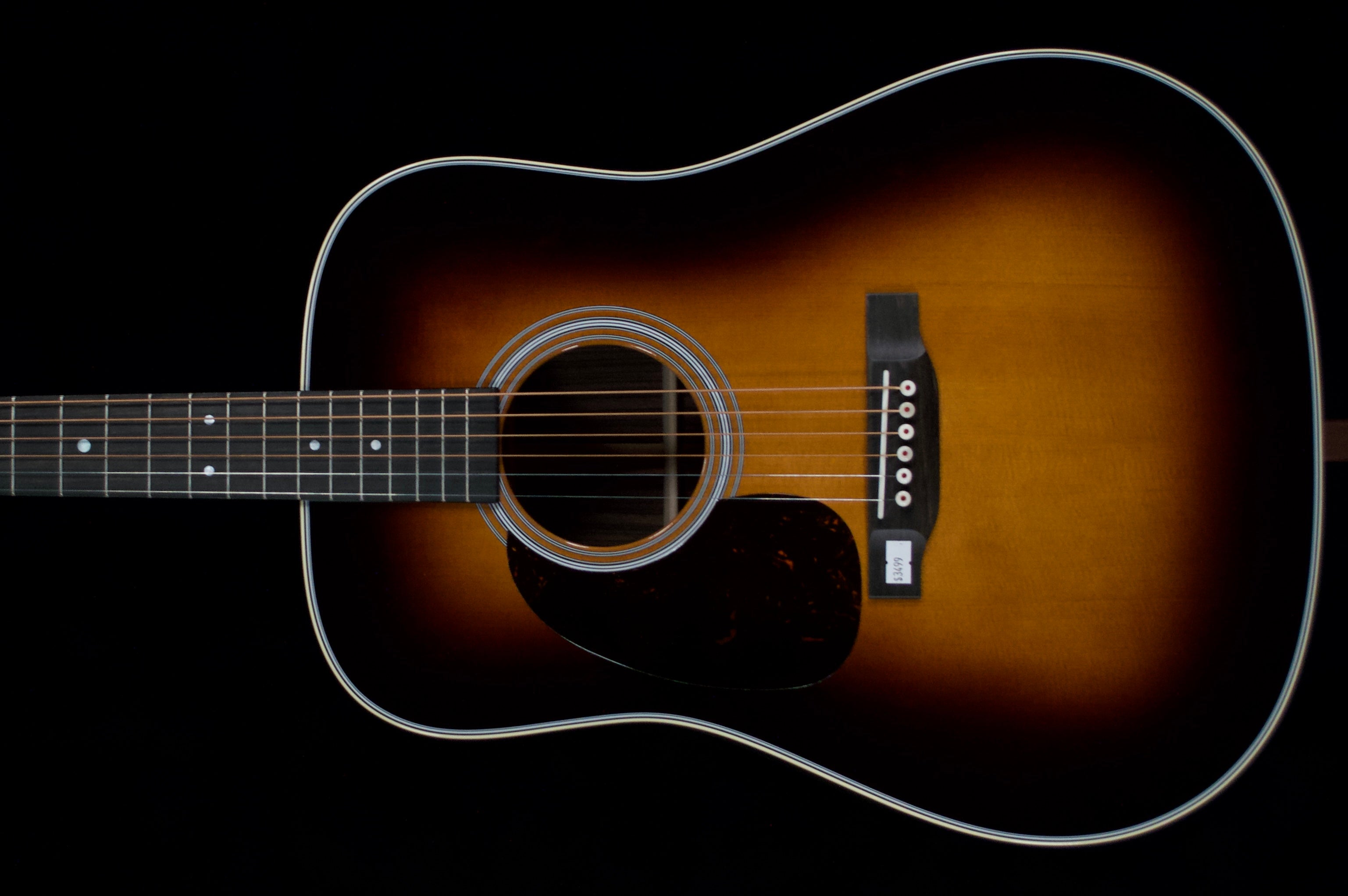 Sunburst Martin D-28 left-handed acoustic guitar with a dark pickguard against a black background
