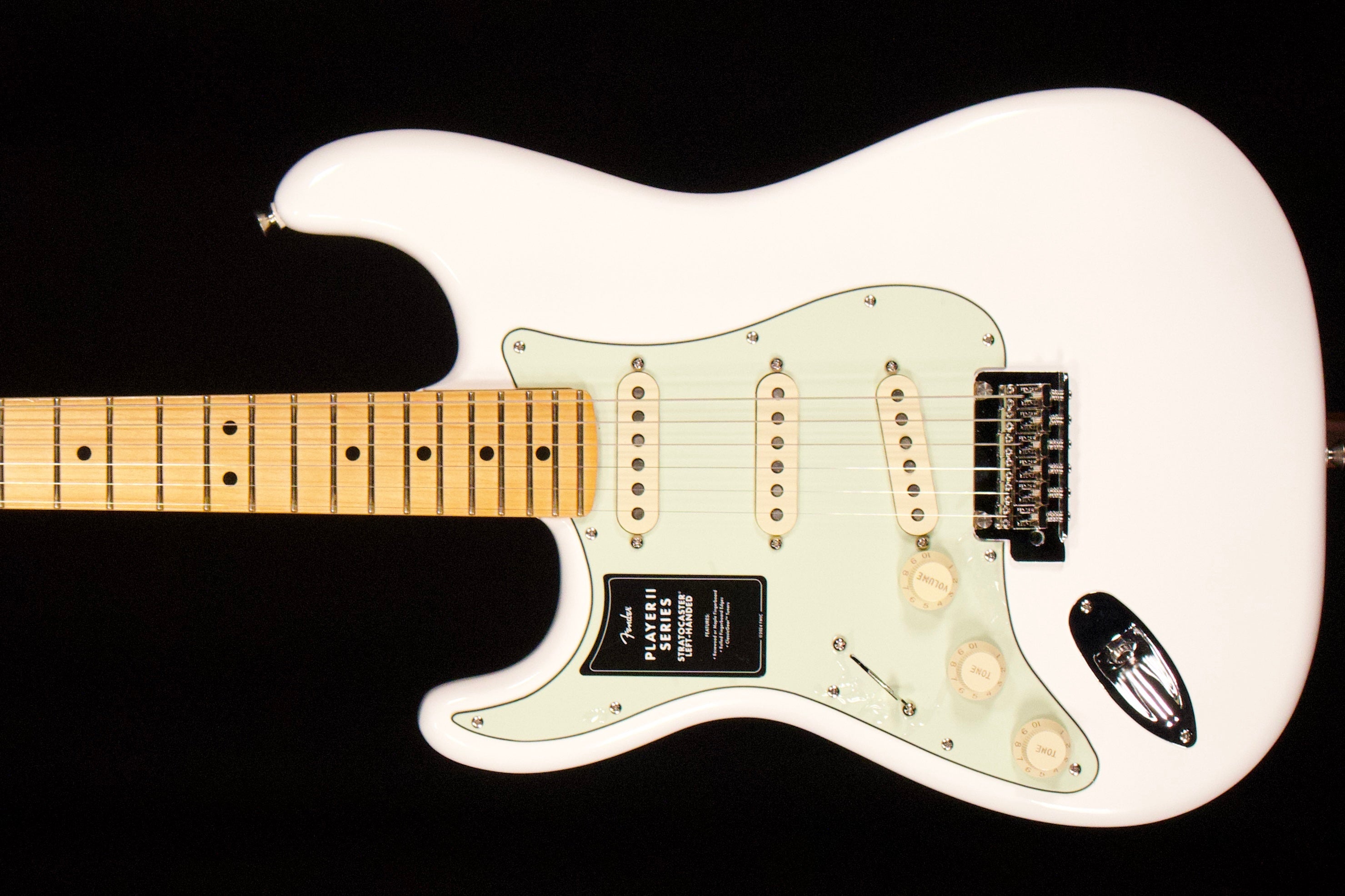 White Fender Player II left-handed Stratocaster with a maple fretboard against a black background