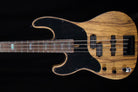 A four-string bass guitar with a natural wood grain body, black pickguard, and black hardware, shown against a solid black background.